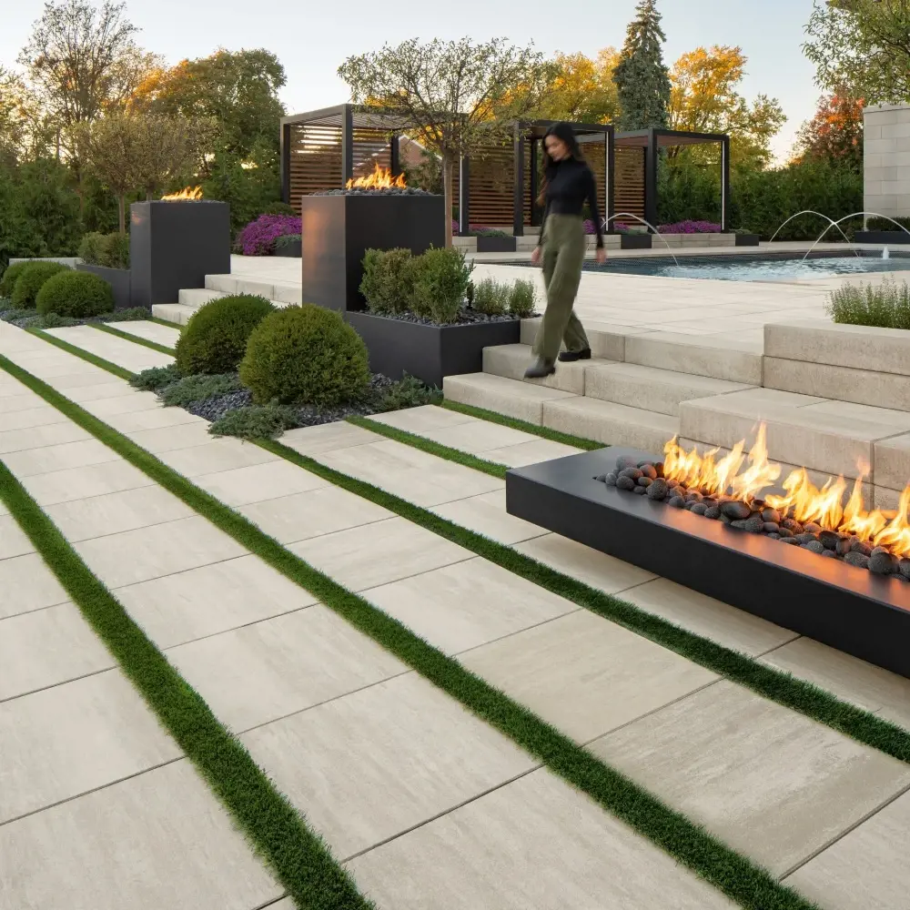 Terrasse arrière moderne avec des dalles de béton Industria posées avec joints gazonnés, des marches Raffinato et des foyers linéaires intégrés.