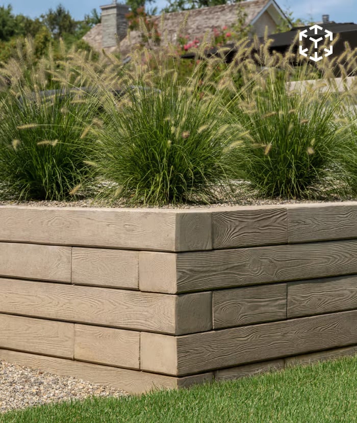 Borealis Wall with a wood-grain textured concrete design used as a retaining border topped with ornamental grasses.