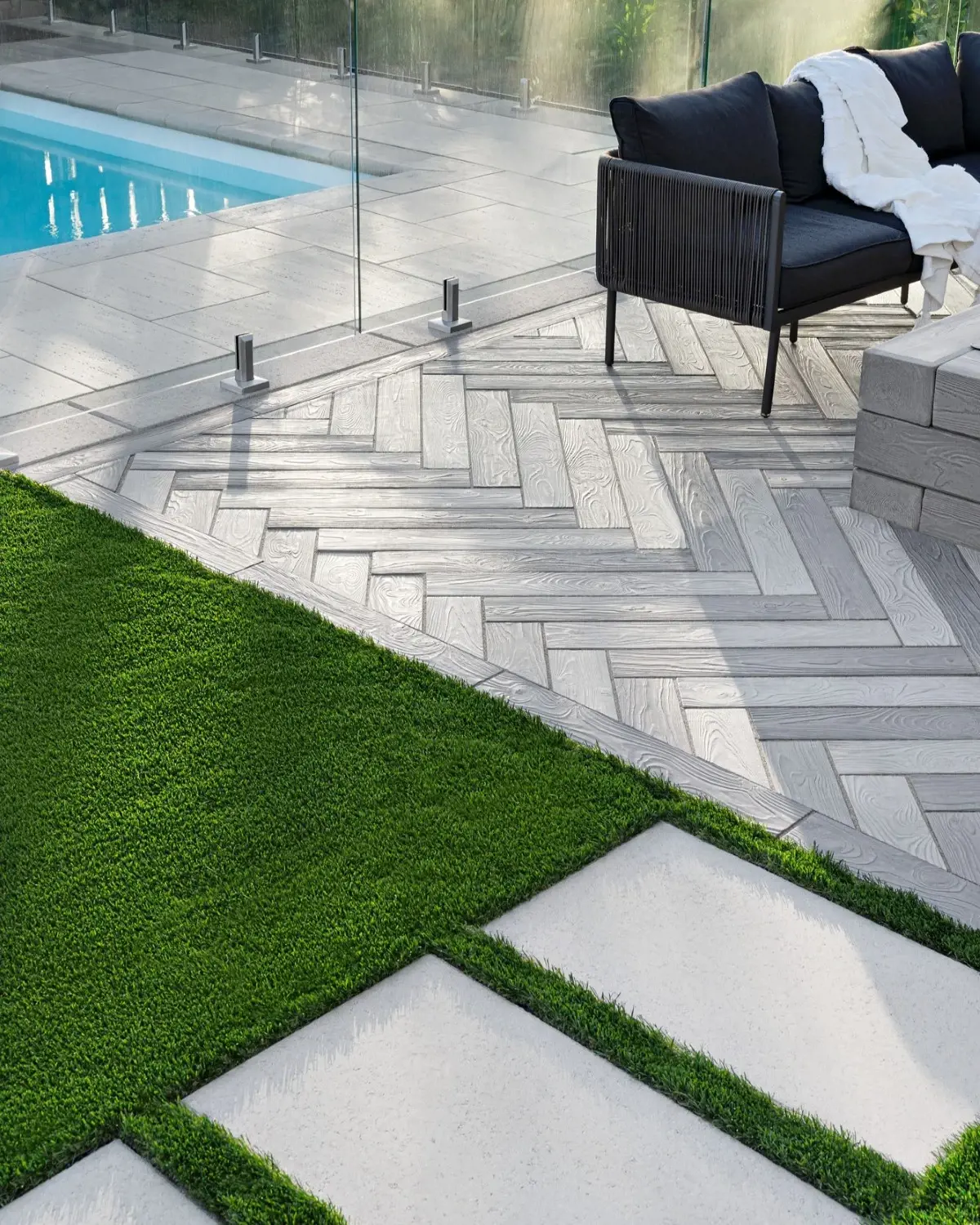 Artificial turf installed beside modern paving around a poolside lounge area.