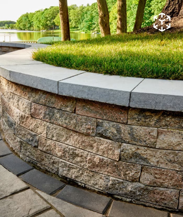 Mini-Creta Architectural Wall with multi-tone textured blocks forming a curved retaining wall along a landscaped lawn.
