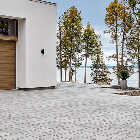 Smooth grey paver driveway and walkway with clean lines in front of a white modern home, using Blu 80 mm HD² by Techo-Bloc.