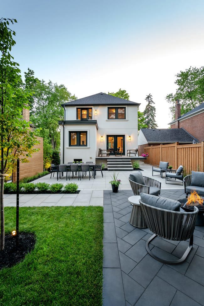 A backyard featuring a dining area with a view of the firepit seating area and the dining area in the background.