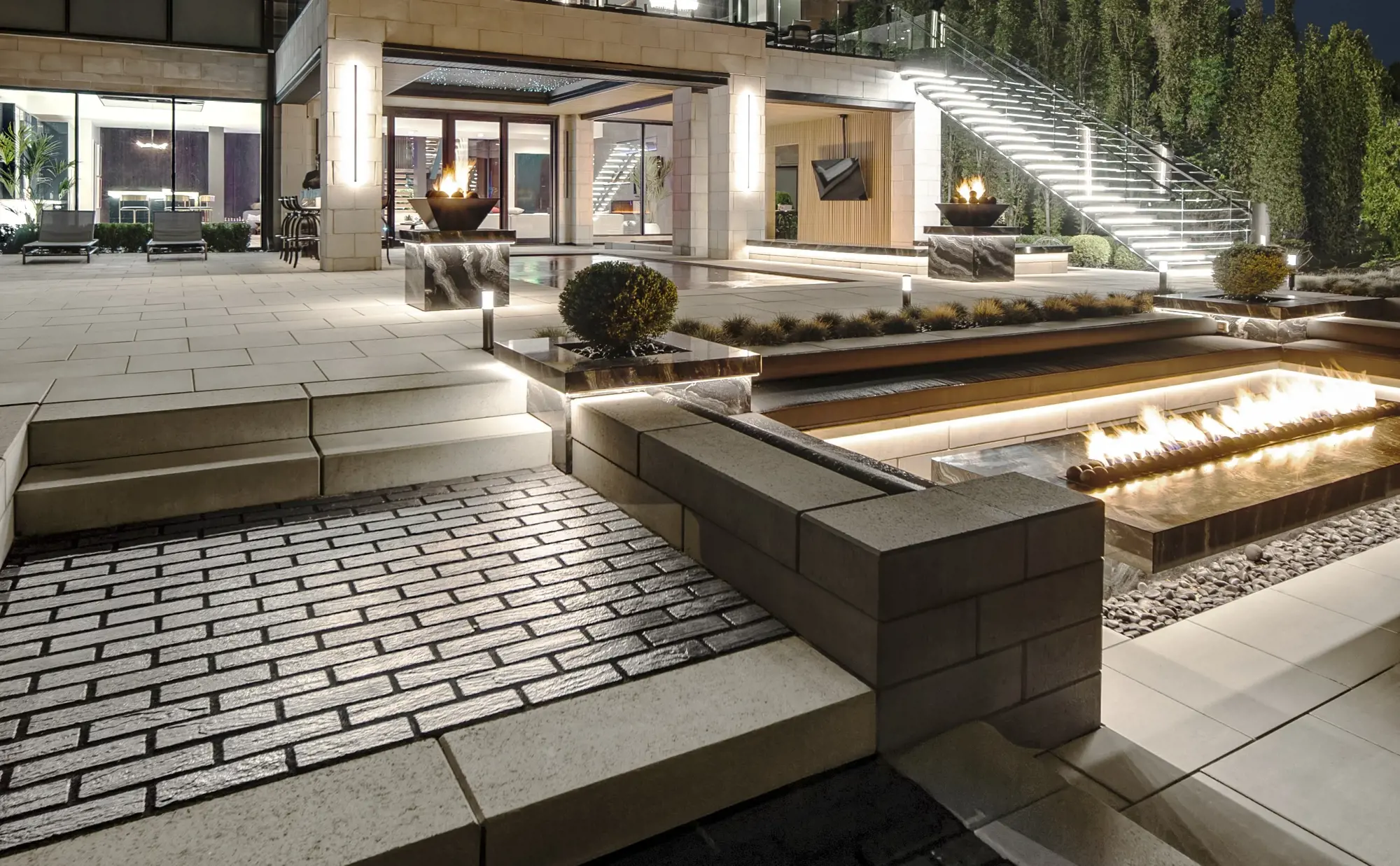 Modern outdoor living space with Techo-Bloc pavers, fire feature, and built-in seating overlooking Lake Michigan.