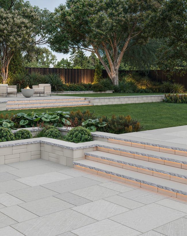 Natural Stone patio with steps leading to a grass lawn.