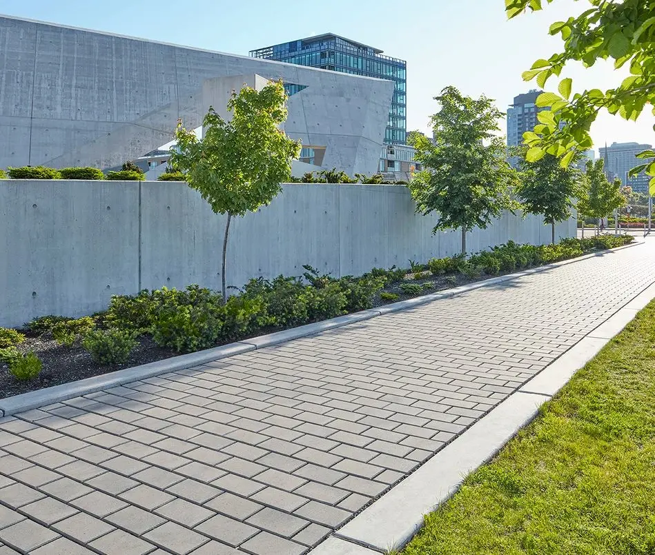 Allée urbaine en pavés Hydra perméables gris clair, avec aménagement paysager et surface plane pour infiltration d’eau.