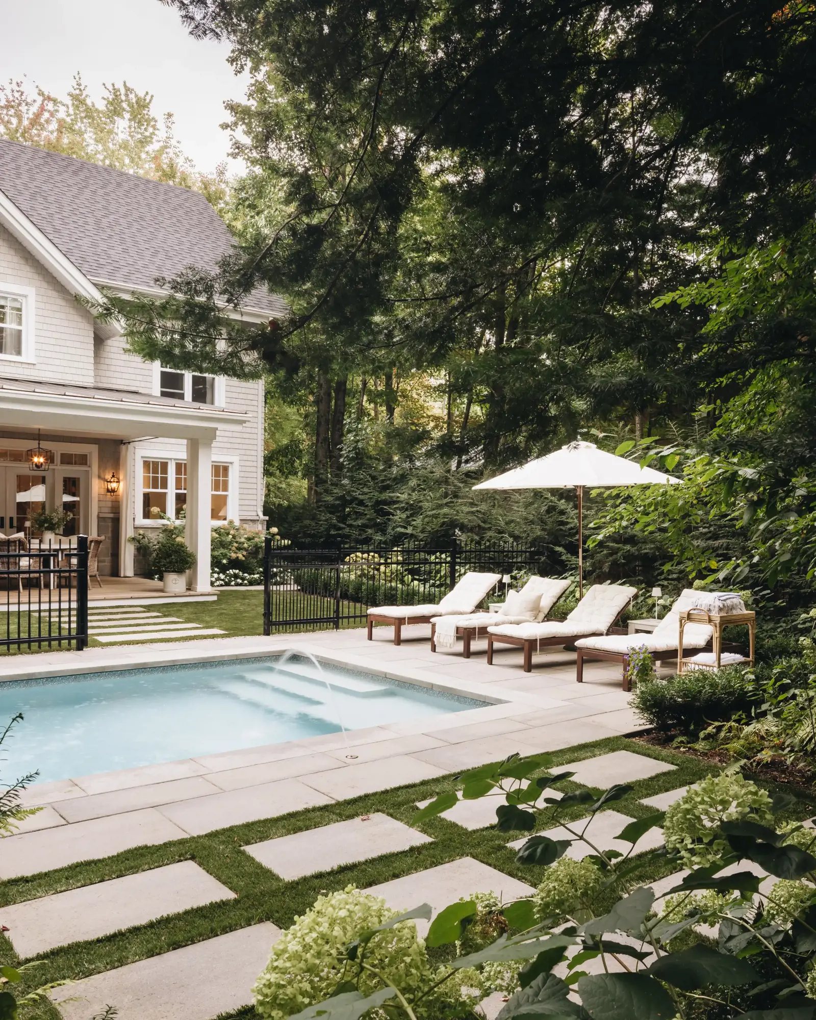 Cour arrière après rénovation avec terrasse en pavé, piscine et coin détente ombragé
