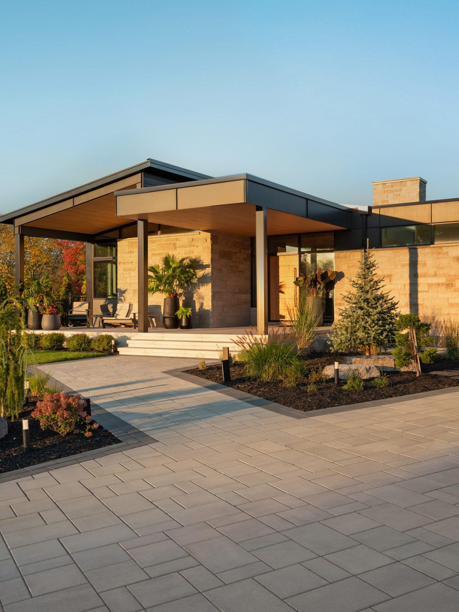 Expansive patio paved with Blu 60 Smooth Slabs in Greyed Nickel, creating a sleek architectural surface that connects the pool, fire feature, and lounge areas.