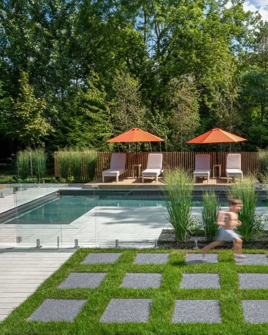 Poolside patio with large square pavers and grass inlays creating a balanced, nature-inspired outdoor retreat.