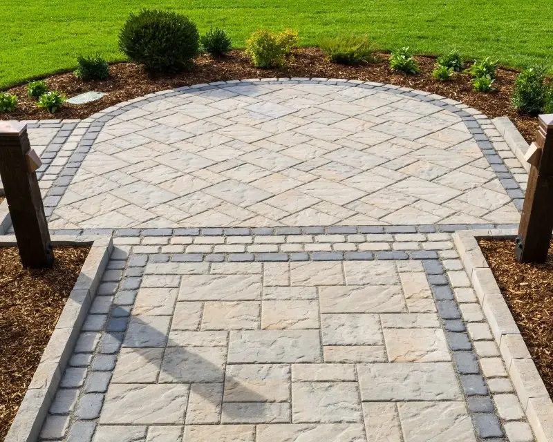 Patio extérieur avec pavés Villagio de Techo-Bloc utilisés pour des bordures et incrustations décoratives, mariant couleurs contrastantes et motifs modulaires pour un style raffiné et intemporel.