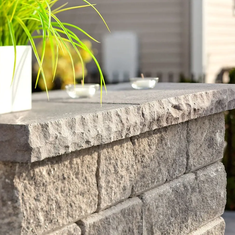 Un muret moderne avec des couronnements York lisses et sculptés, imitant la pierre naturelle, dans un environnement de jardin bien entretenu.