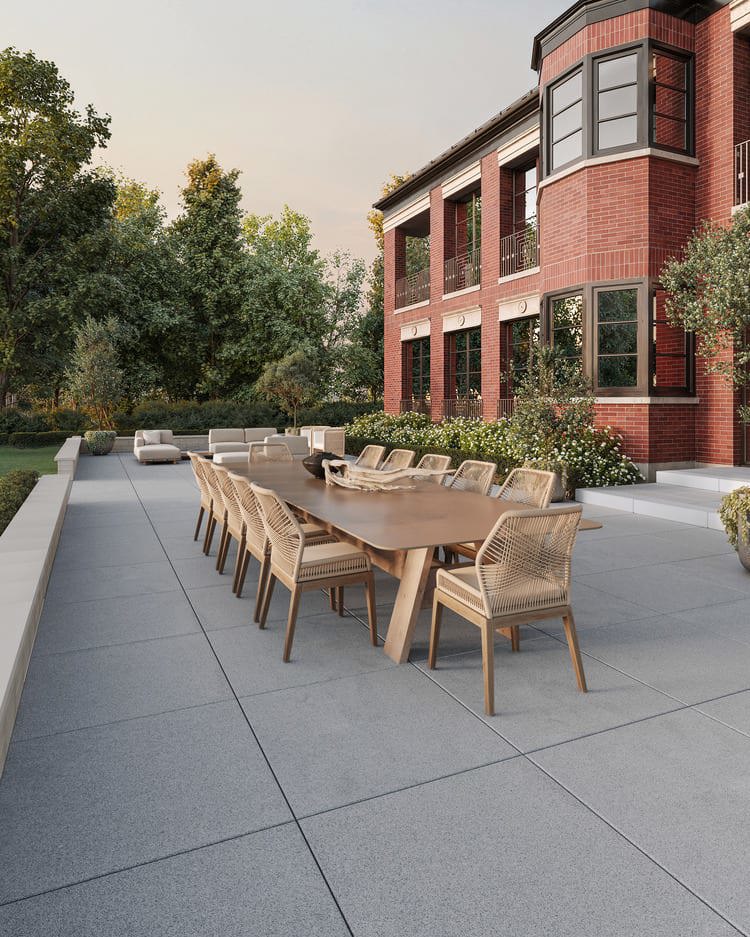 Terrasse ext&#xE9;rieure avec salle &#xE0; manger et dalles en pierre naturelle de couleur grise.