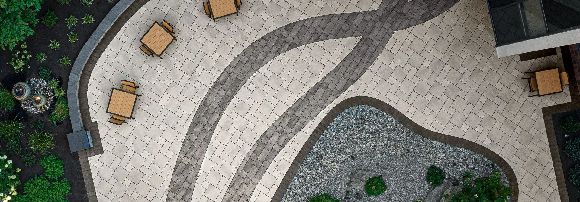 Patio en dalle Everest de Techo-Bloc en Greyed Nickel et Shale Grey, avec texture lisse et courbes décoratives.