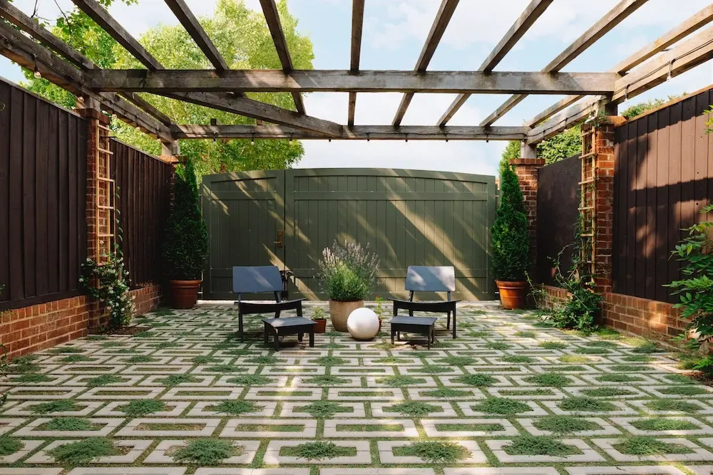 Photo après d’une petite cour arrière rénovée avec les pavés perméables Aquastorm de Techo-Bloc, des joints engazonnés, un coin détente, de la verdure et une pergola.
