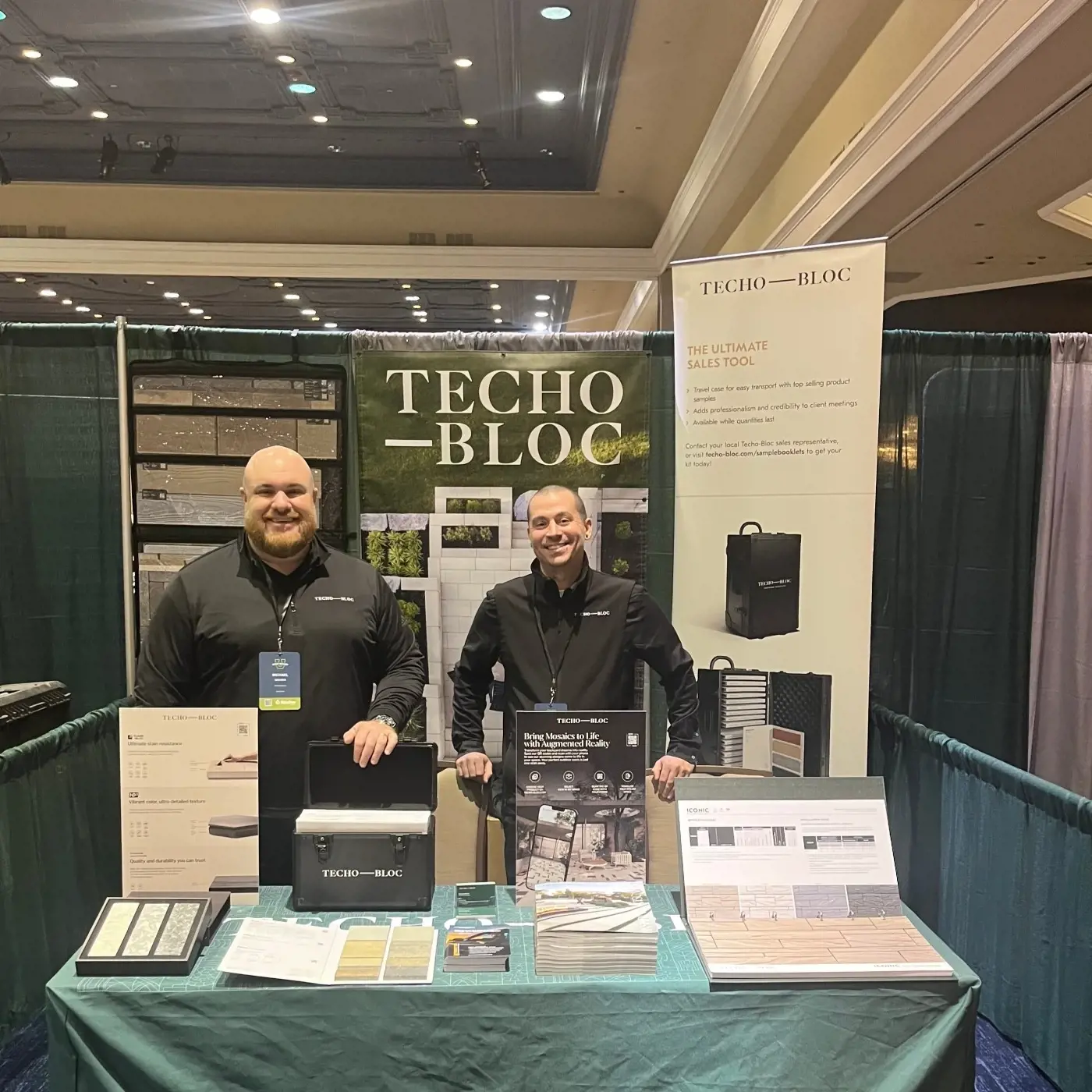Techo-Bloc representatives hosting a contractor training event booth showcasing pavers, slabs, retaining wall systems, and outdoor design materials.