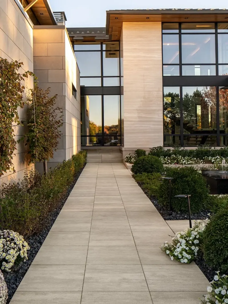 Allée de jardin en pavés texturés traversant un aménagement paysager