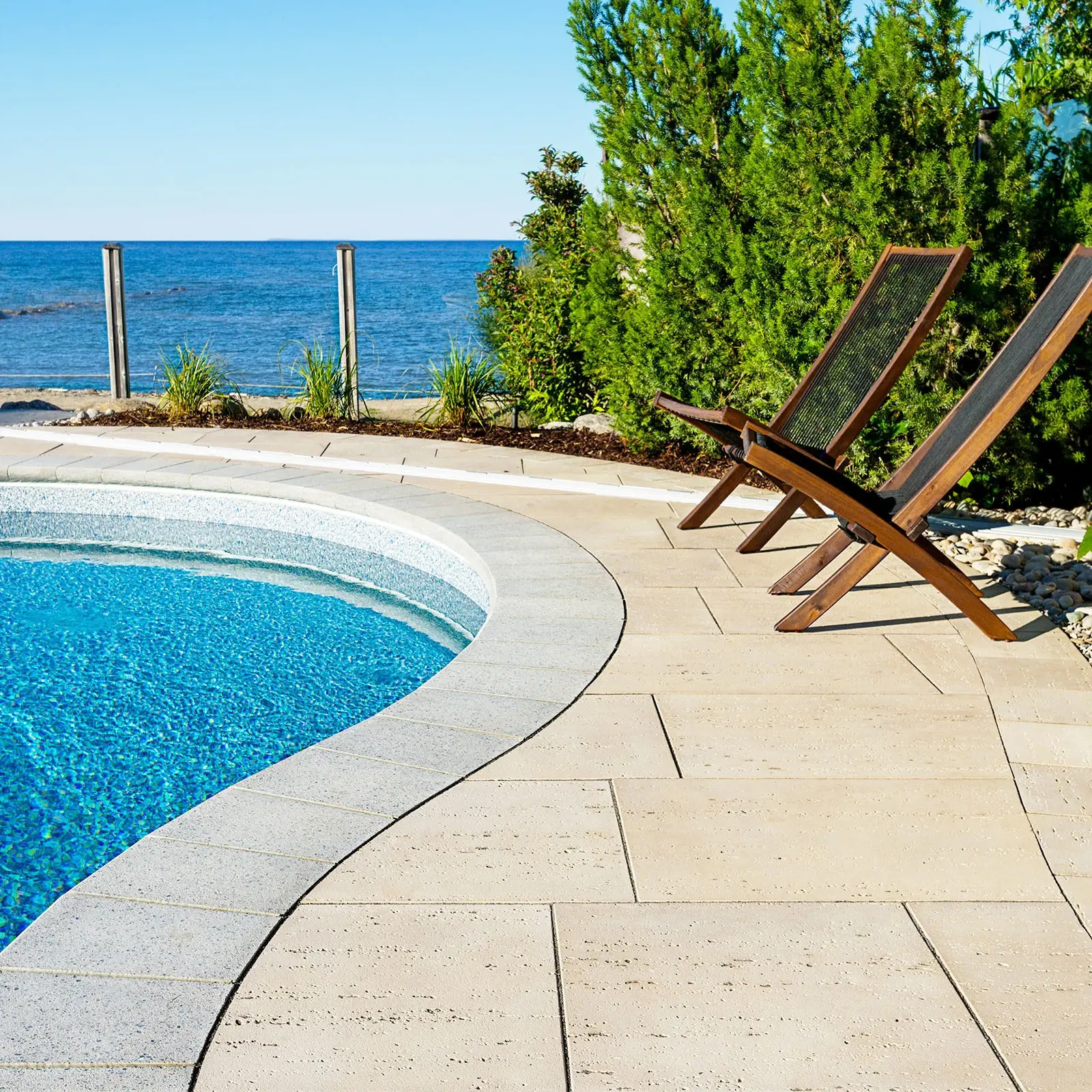 Bullnose Cap in Shale Grey Smooth as pool edge coping beside patio lounge chairs