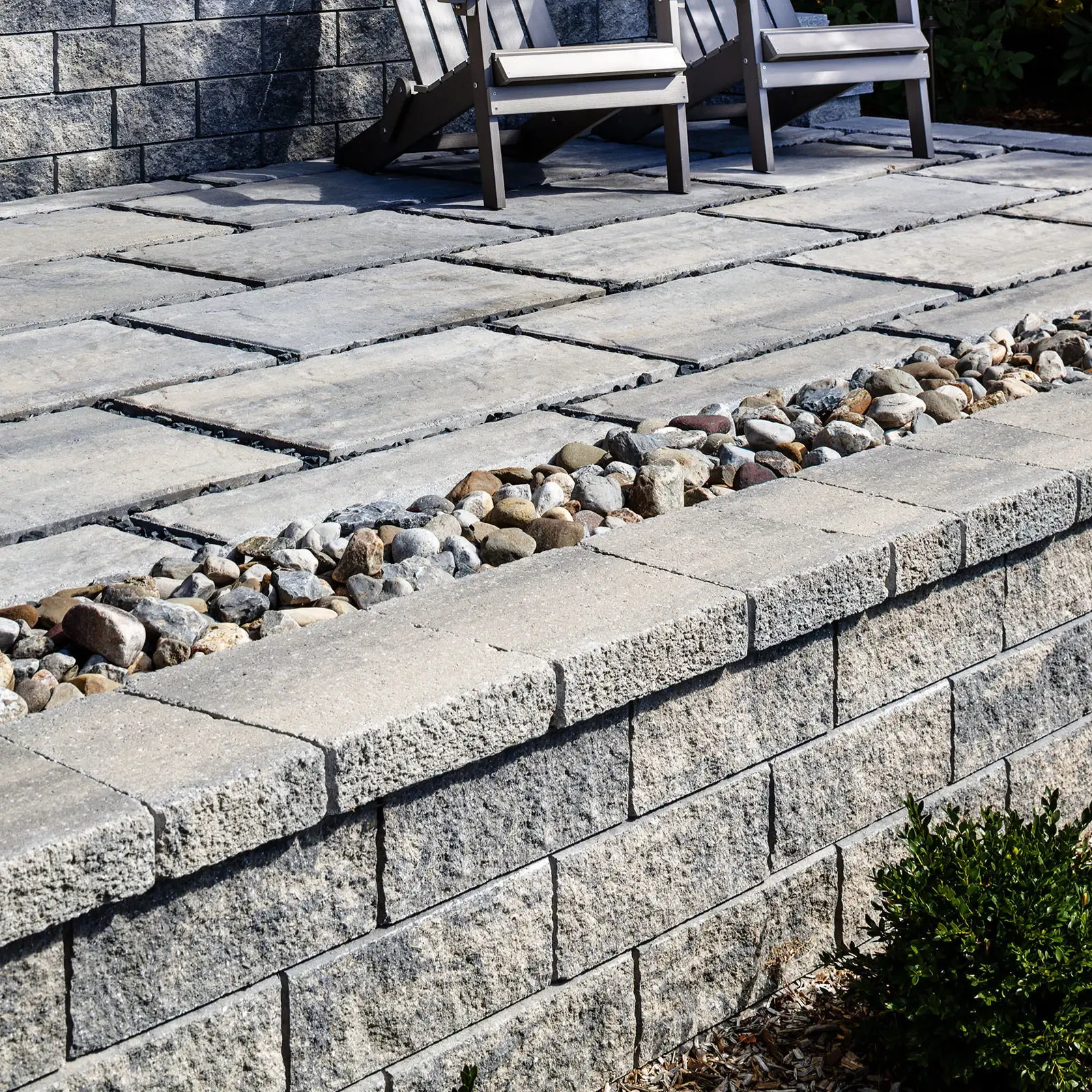 Architectural Cap in Shale Grey topping a garden wall beside river rock and large patio slabs