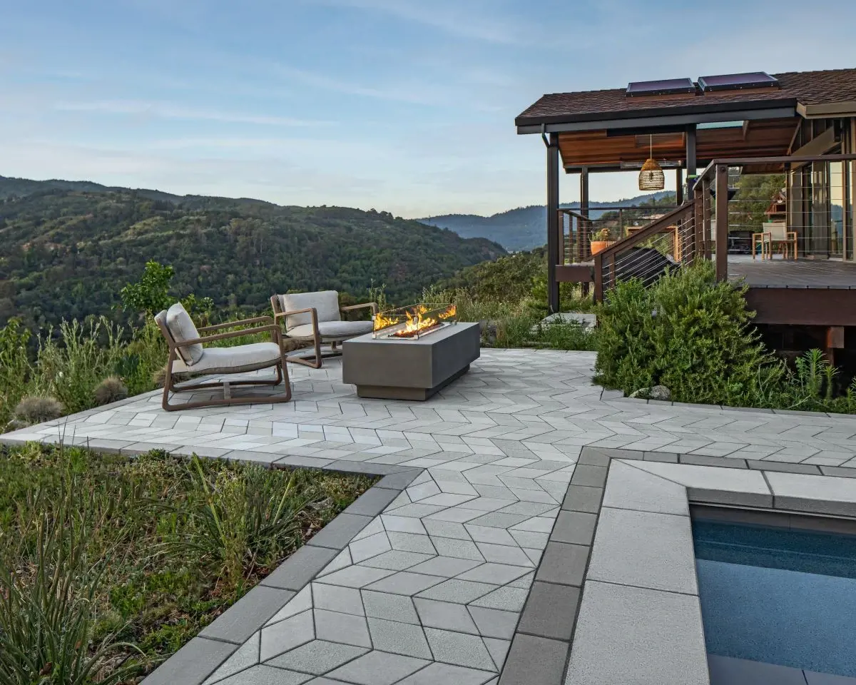 Terrasse moderne en dalles Para et pavés Diamond avec bordures Raffinato, offrant un coin feu et une vue sur les montagnes.
