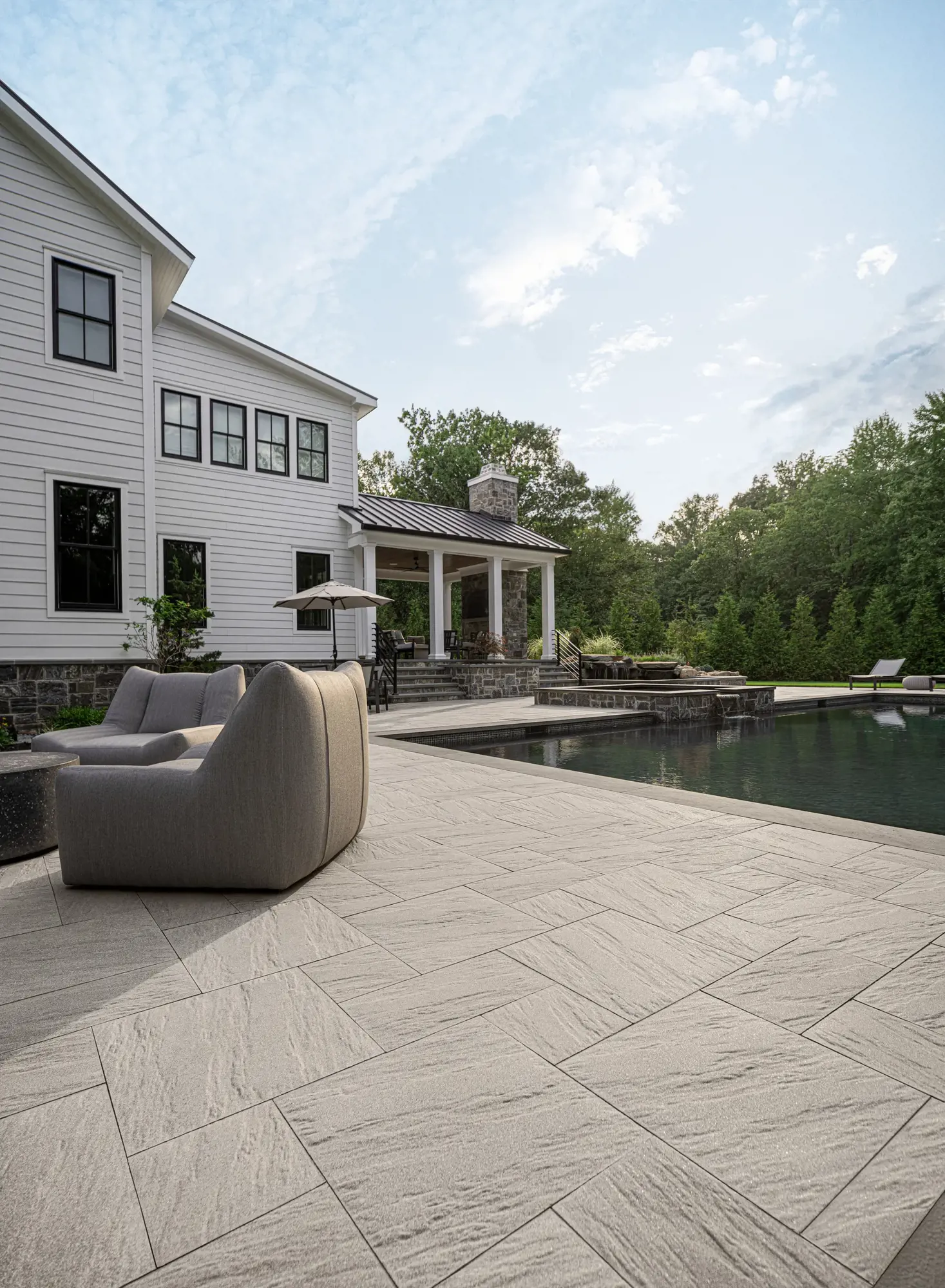 Contemporary poolside patio surfaced with Techo-Bloc Everest Slabs in Greyed Nickel, showcasing large-format stone texture and clean lines.