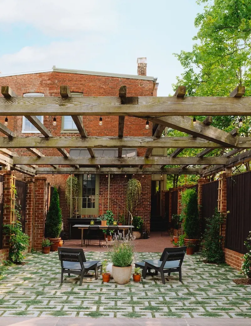 Cour arrière chaleureuse avec pavés perméables Aquastorm de Techo-Bloc, joints engazonnés, coin détente, verdure et pergola.
