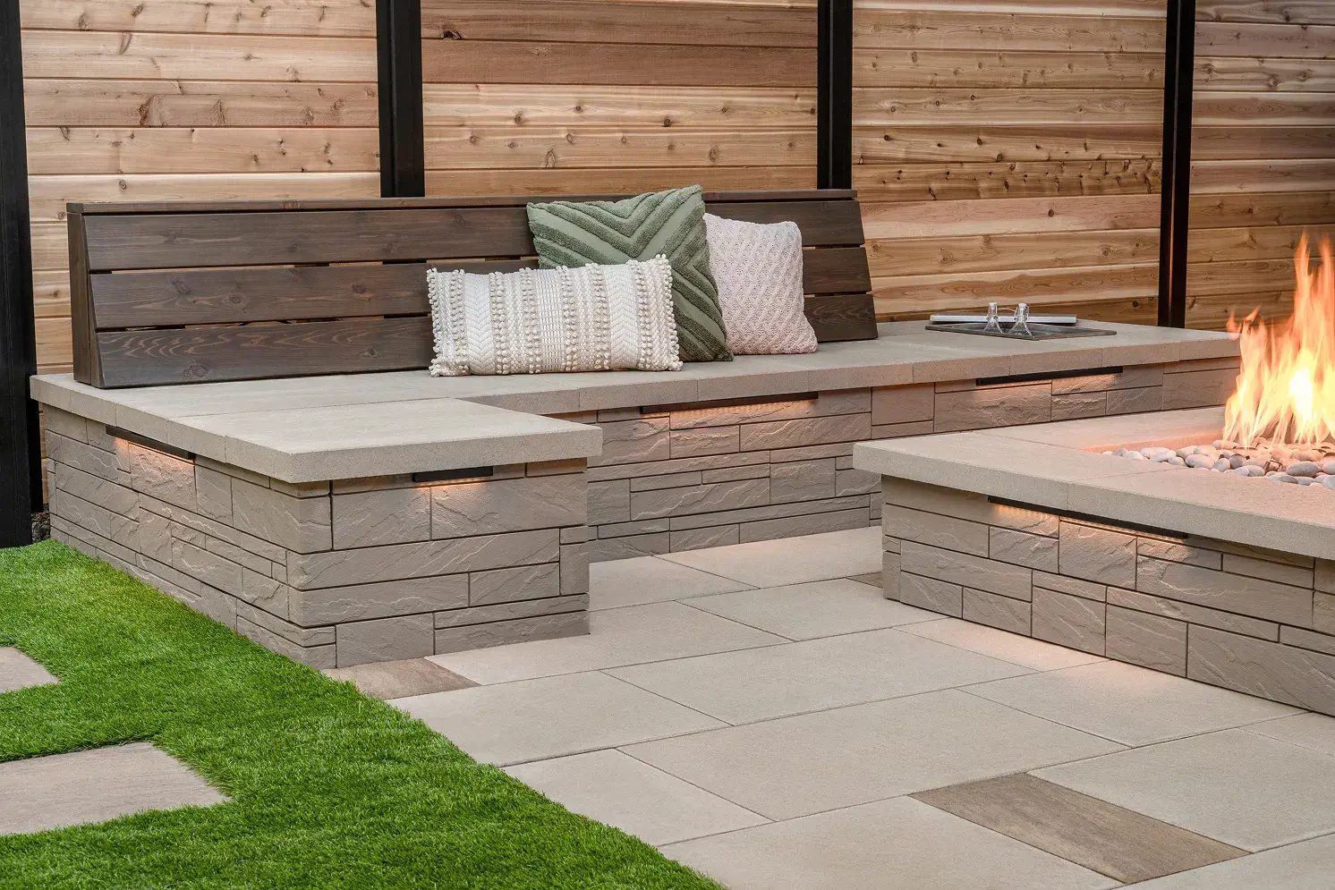 Foyer au gaz allumé sur le patio de dalles, avec pouf tricoté et banc à coussins