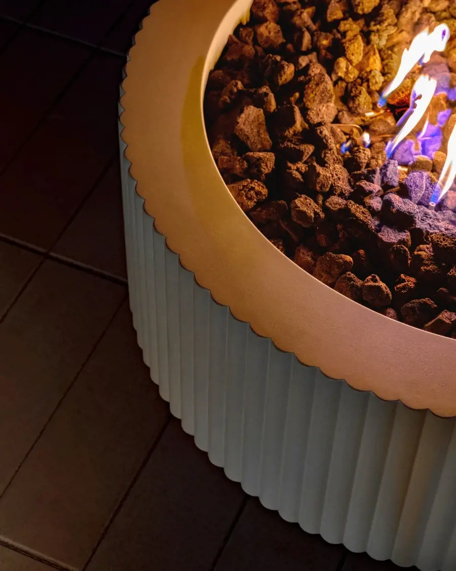 Close-up view of a Sculptura fire pit highlighting its fluted texture, smooth contours, and elegant flame presentation.