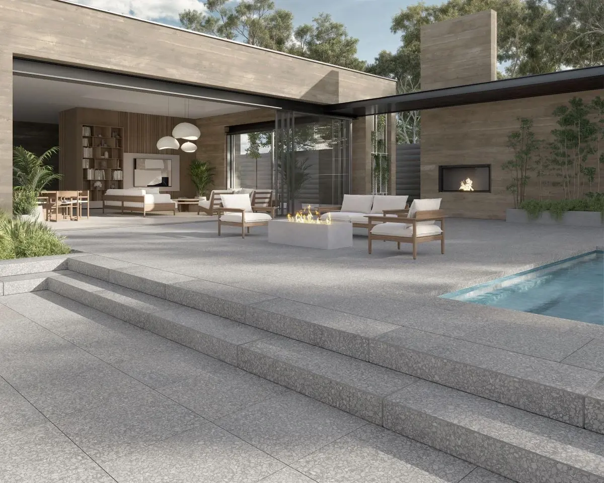 Terrasse extérieure avec piscine, escaliers larges et coin détente moderne, aménagée avec les dalles et marches gris pâle de la collection Terrazzo de Techo-Bloc.