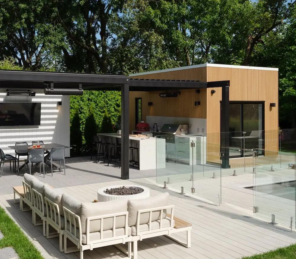 Modern backyard designed with Techo-Bloc Industria pavers and Terrazzo slabs, pool, outdoor kitchen, covered dining area, lounge seating, and fire feature.