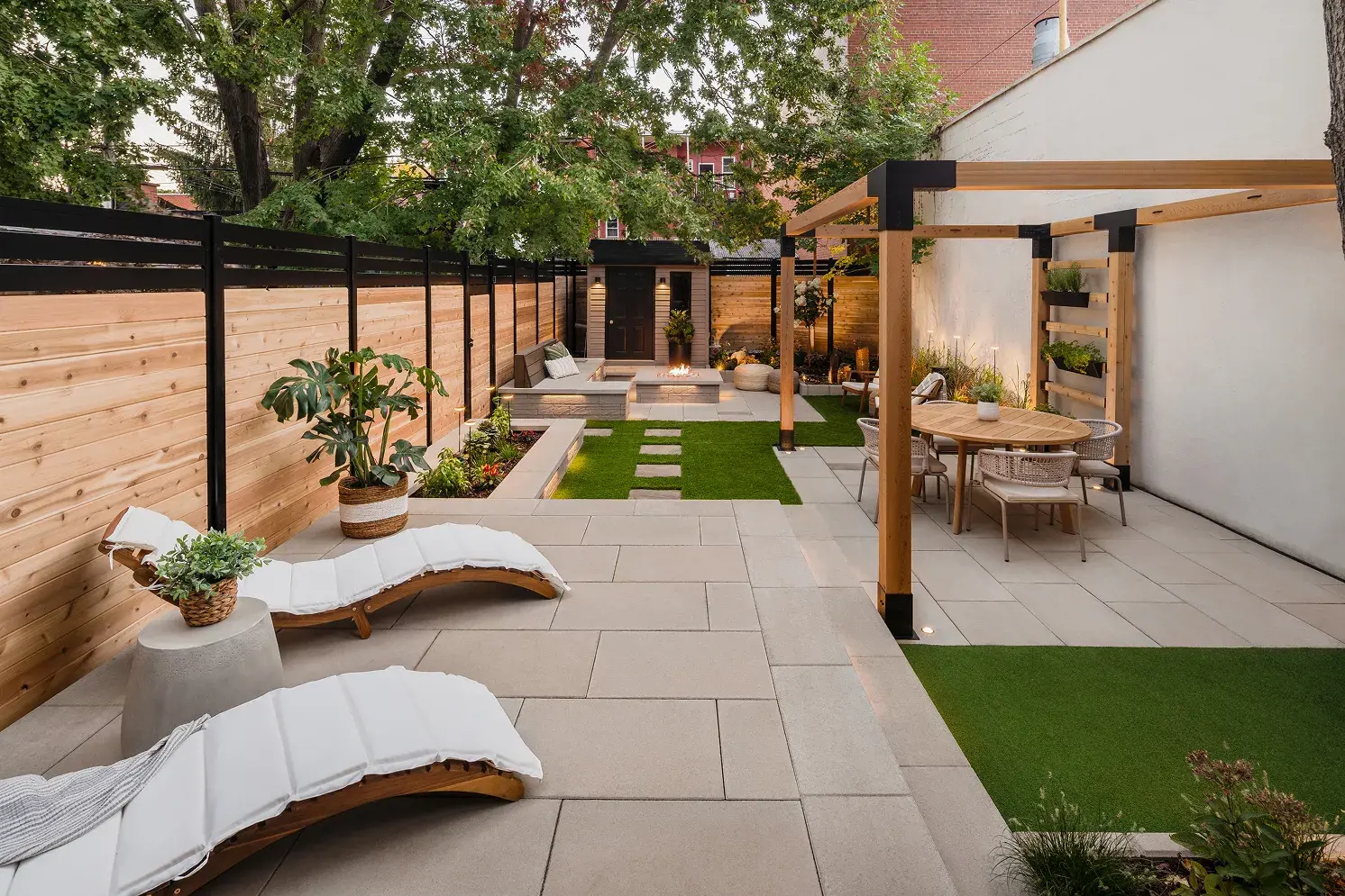 Cour arrière aménagée à Montréal avec coin repas sous pergola, foyer au gaz et patio de dalles