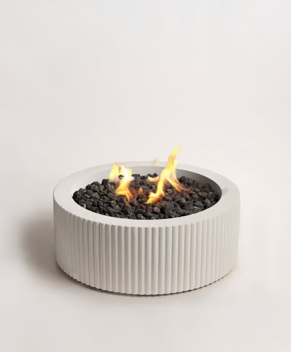 Sculptura Scalloped Fire Pit featuring a ribbed round concrete design with a central flame over black fire stones.