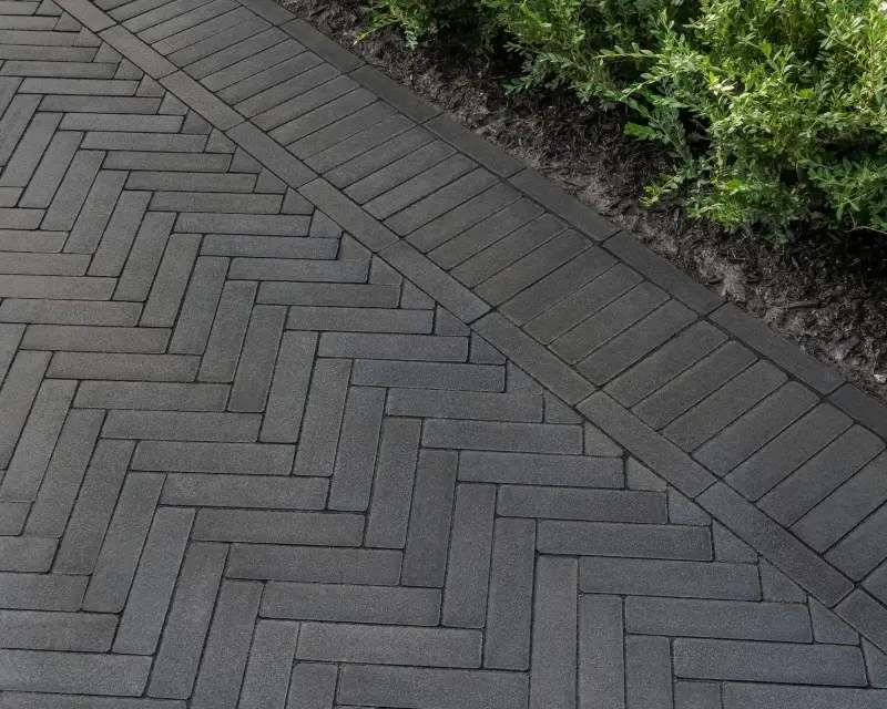 Gros plan sur des pavés Westmount de Techo-Bloc utilisés comme bordures et accents paysagers modernes, avec lignes épurées, arêtes précises et motif chevron raffiné.