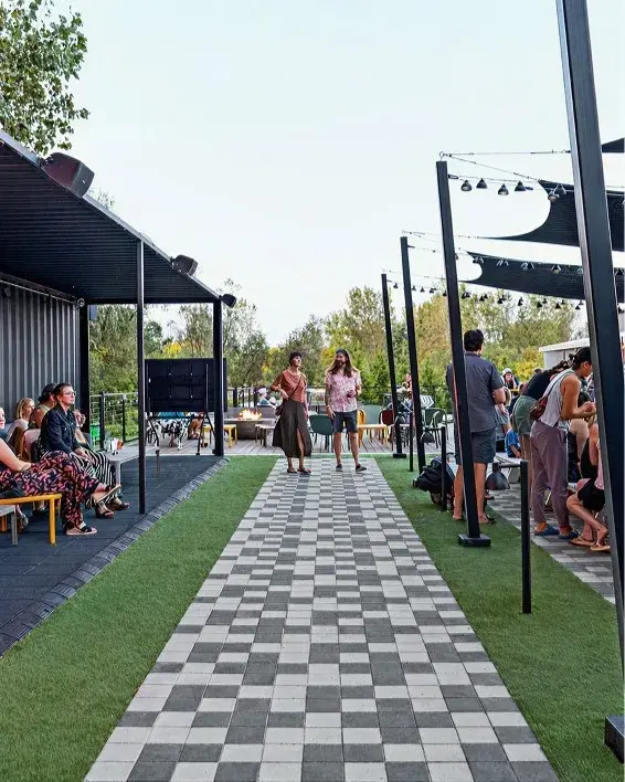Pavés Industria en disposition linéaire noir et gris au Yard at Sam Hill, un espace extérieur animé.