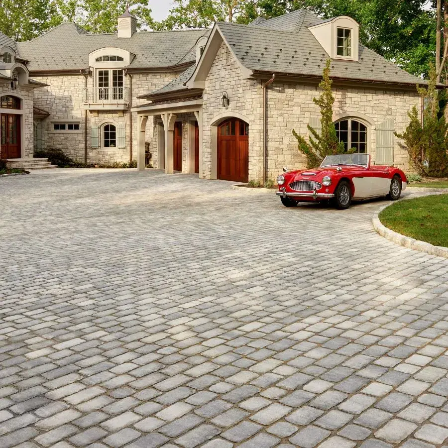 Villagio Paver by Techo-Bloc in Shale Grey with rustic cobblestone texture, creating a charming walkway beneath a covered garden corridor.