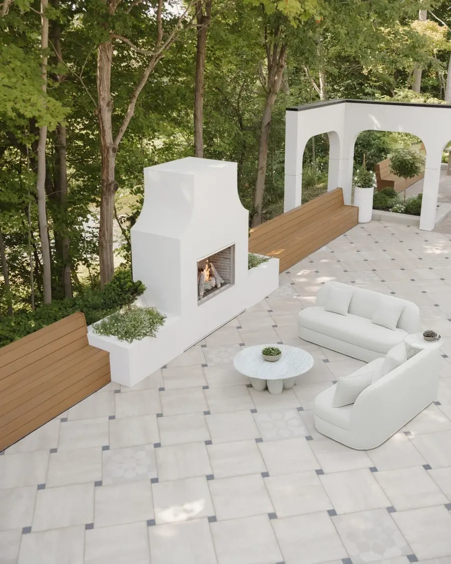 Tranquil courtyard space surfaced with Industria 600×600 slabs in Caffè Crema, paired with a sculptural fireplace and neutral outdoor seating.