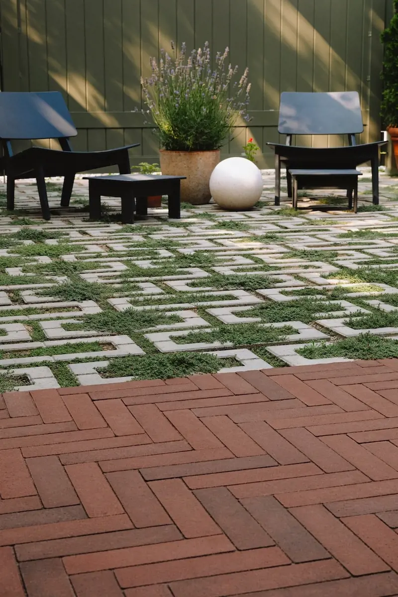 Gros plan des pavés perméables Aquastorm de Techo-Bloc avec joints engazonnés près d’un coin détente et des pavés Westmount.