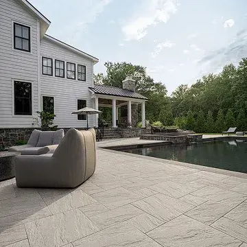 A peaceful patio featuring comfortable seating and Everest Slab in Greyed Nickel, providing a smooth, modern surface for outdoor relaxation.