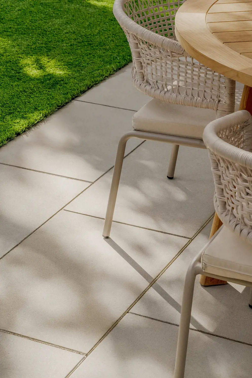 Gros plan de chaises tressées et d'une table sur le patio de dalles sous une lumière tamisée