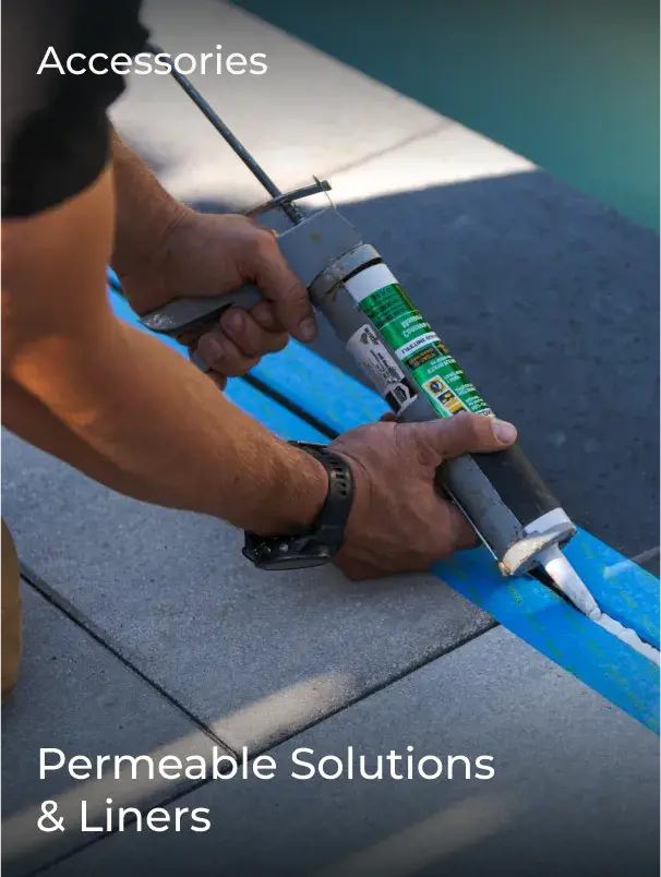 Person applying adhesive along a seam between pavers, using a blue liner to support a permeable surface installation.