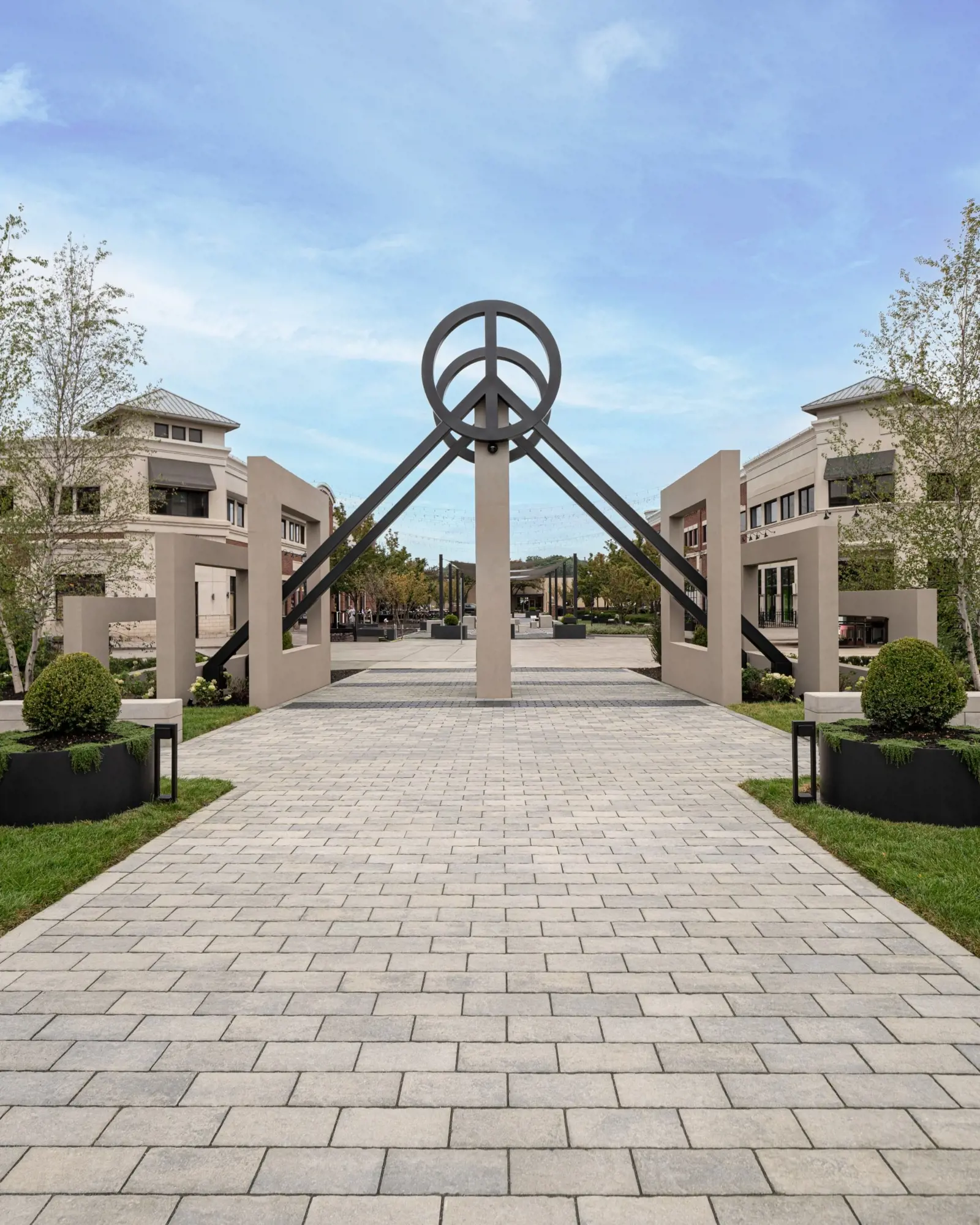 Allée du Peace Park pavée de Blu 60 HD² Smooth en tons de gris, guidant les visiteurs vers la sculpture centrale du logo de la paix.