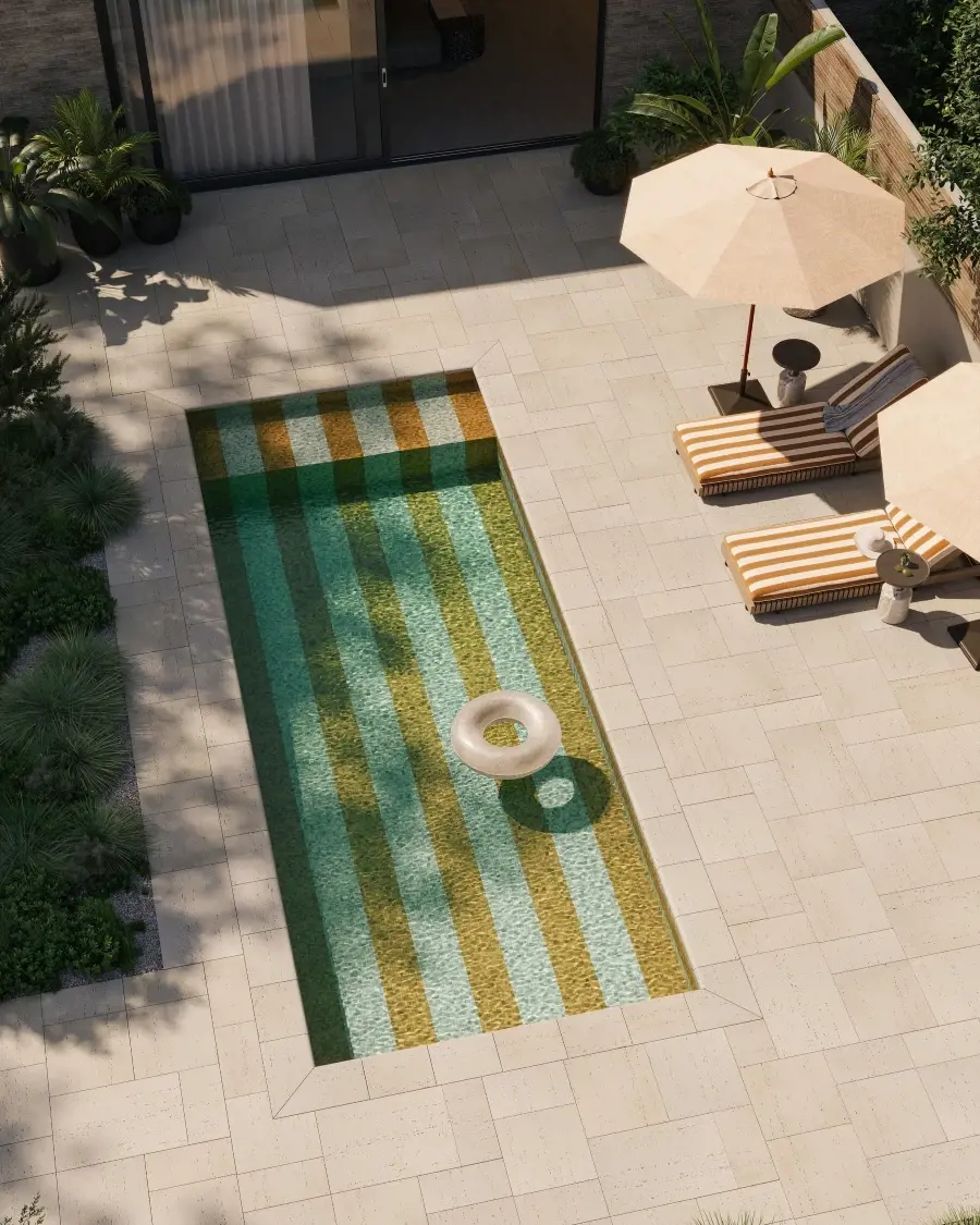 Poolside terrace inspired by European coastal design, featuring light stone paving, patterned accents, and relaxed seating for a refined summer atmosphere.