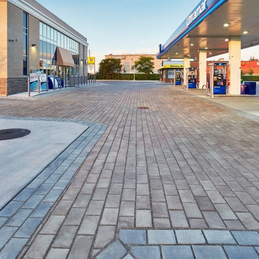 Stationnement commercial d’une station-service aménagé avec des pavés Hydra de Techo-Bloc, offrant une gestion perméable des eaux pluviales et une efficacité durable.