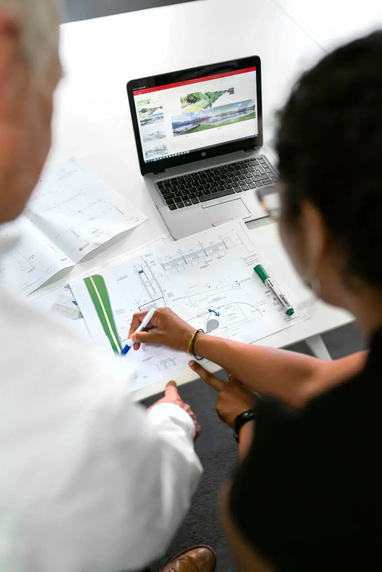 Engineers reviewing technical drawings and material samples at a workspace.