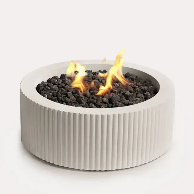 Sculptura Fire Pit Scalloped by Techo-Bloc, scalloped circular fire pit with lava rock, adding a unique, stylish feature to your outdoor space.