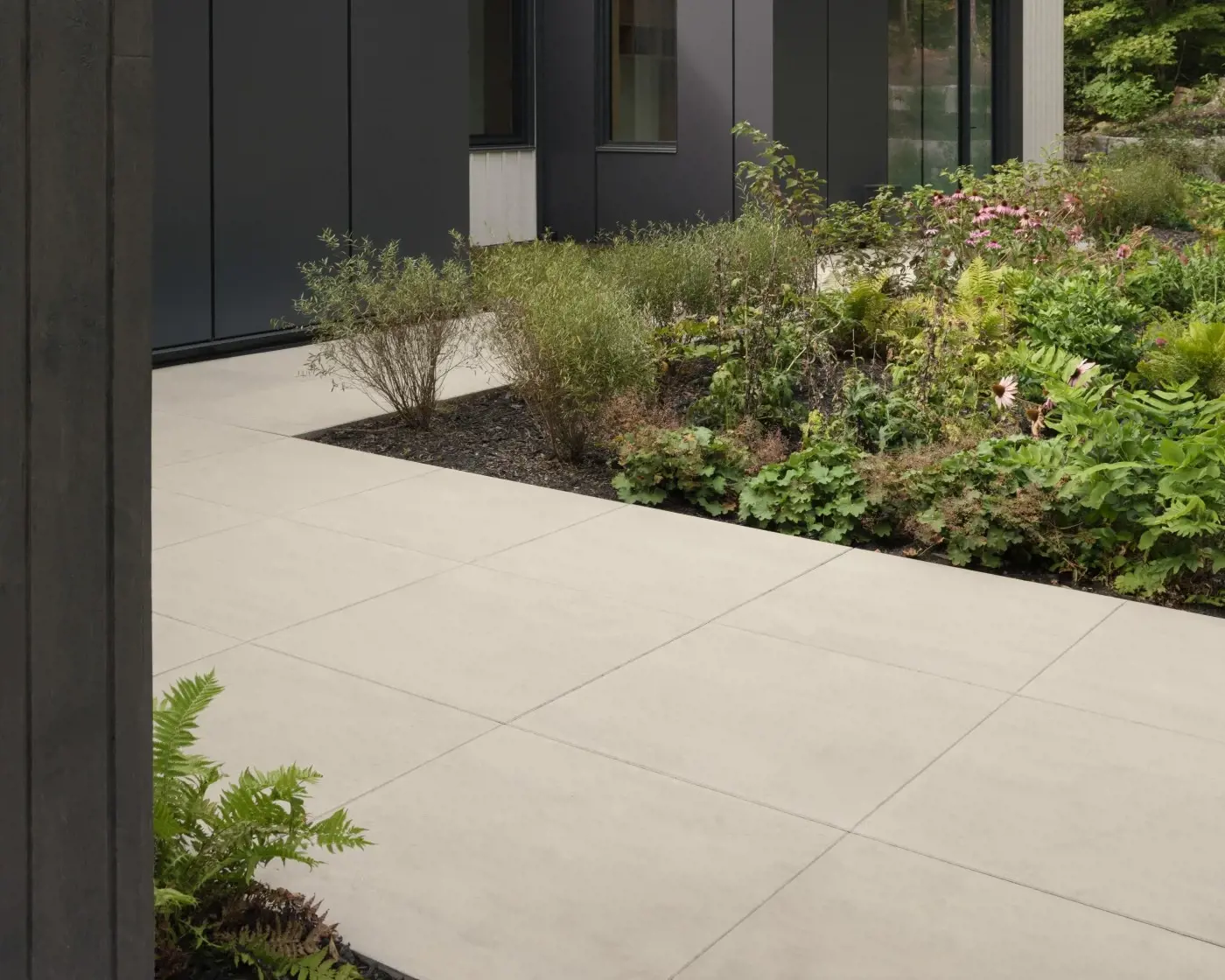 Allée de cour moderne en dalles grand format Para de Techo-Bloc, aux lignes nettes et joints serrés, adjacente à un aménagement paysager verdoyant et structuré.