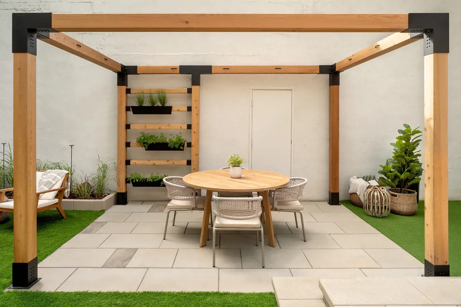 Table à manger ronde et chaises tressées contre un mur blanc, avec jardinière verticale
d'herbes