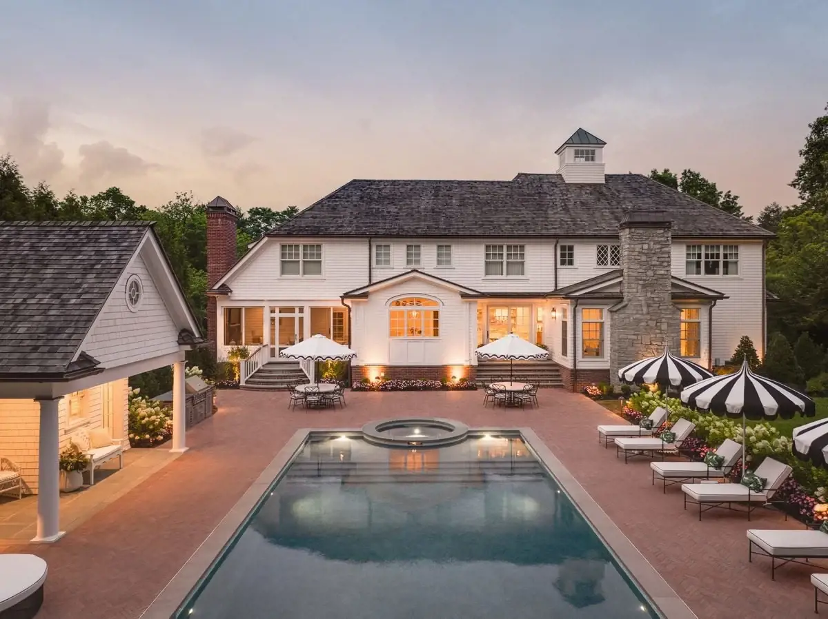 Renovated retro-style backyard featuring modern Techo-Bloc pavers surrounding a reflective pool.