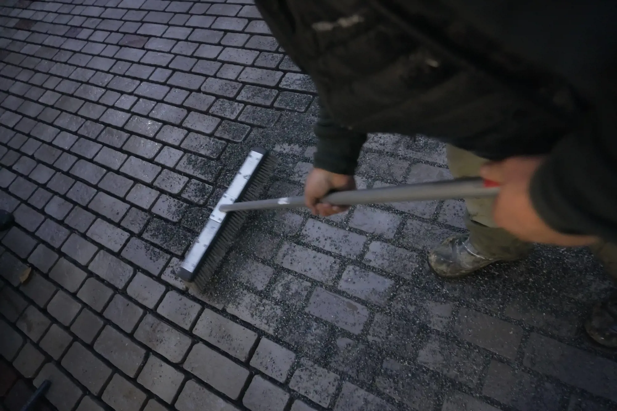 Balayage de sable polymère dans les joints de pavés unis avec un balai-poussoir