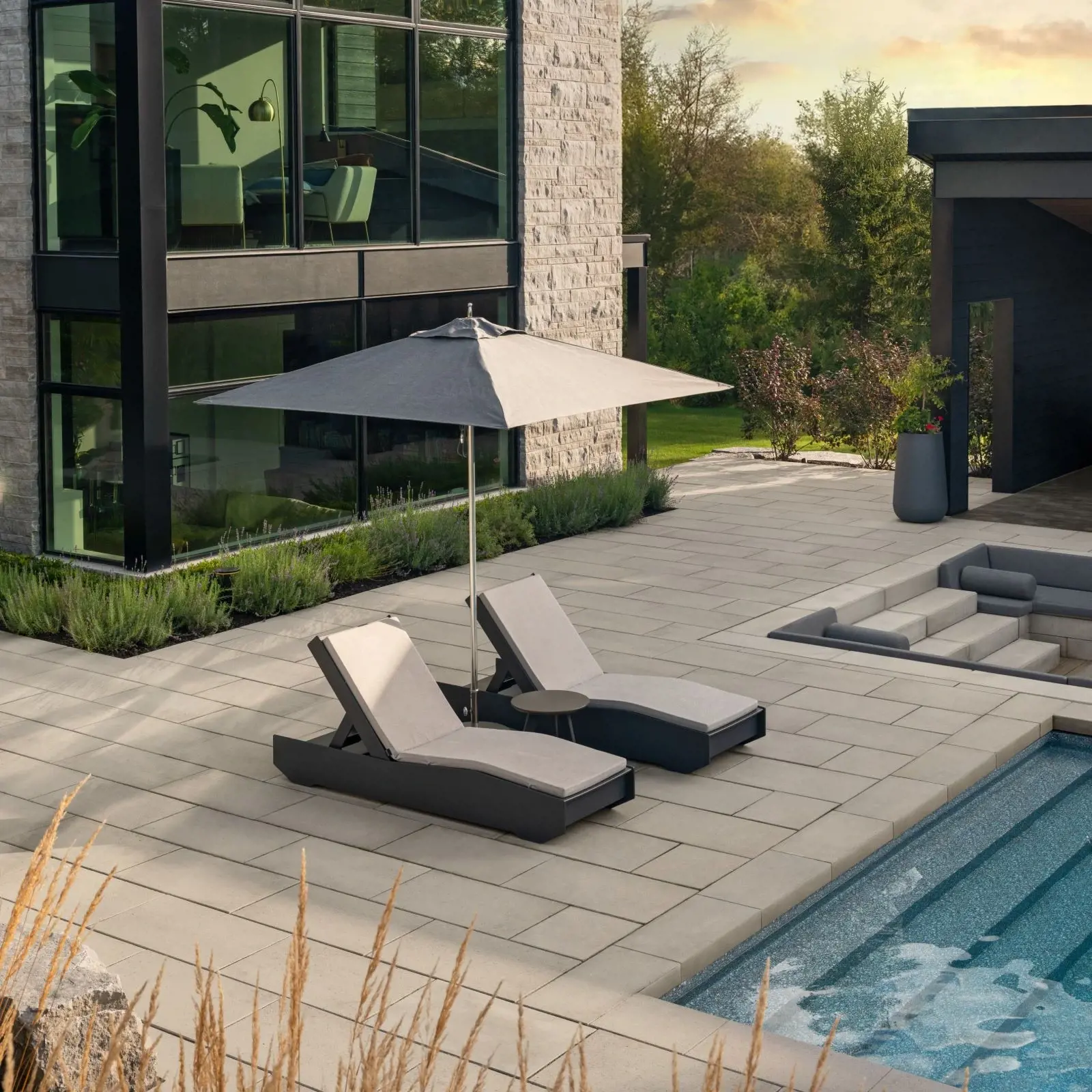 BLU 80 MM HD² paver in Beige Cream with smooth texture, forming spacious poolside patio with loungers and umbrella.