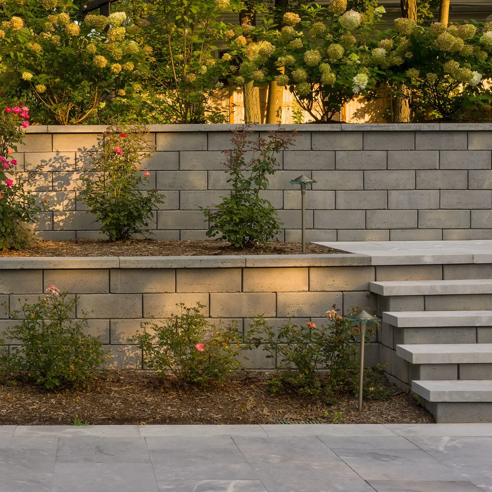 Travertina Raw wall in Riviera shown with garden walls, steps and soft landscape lighting