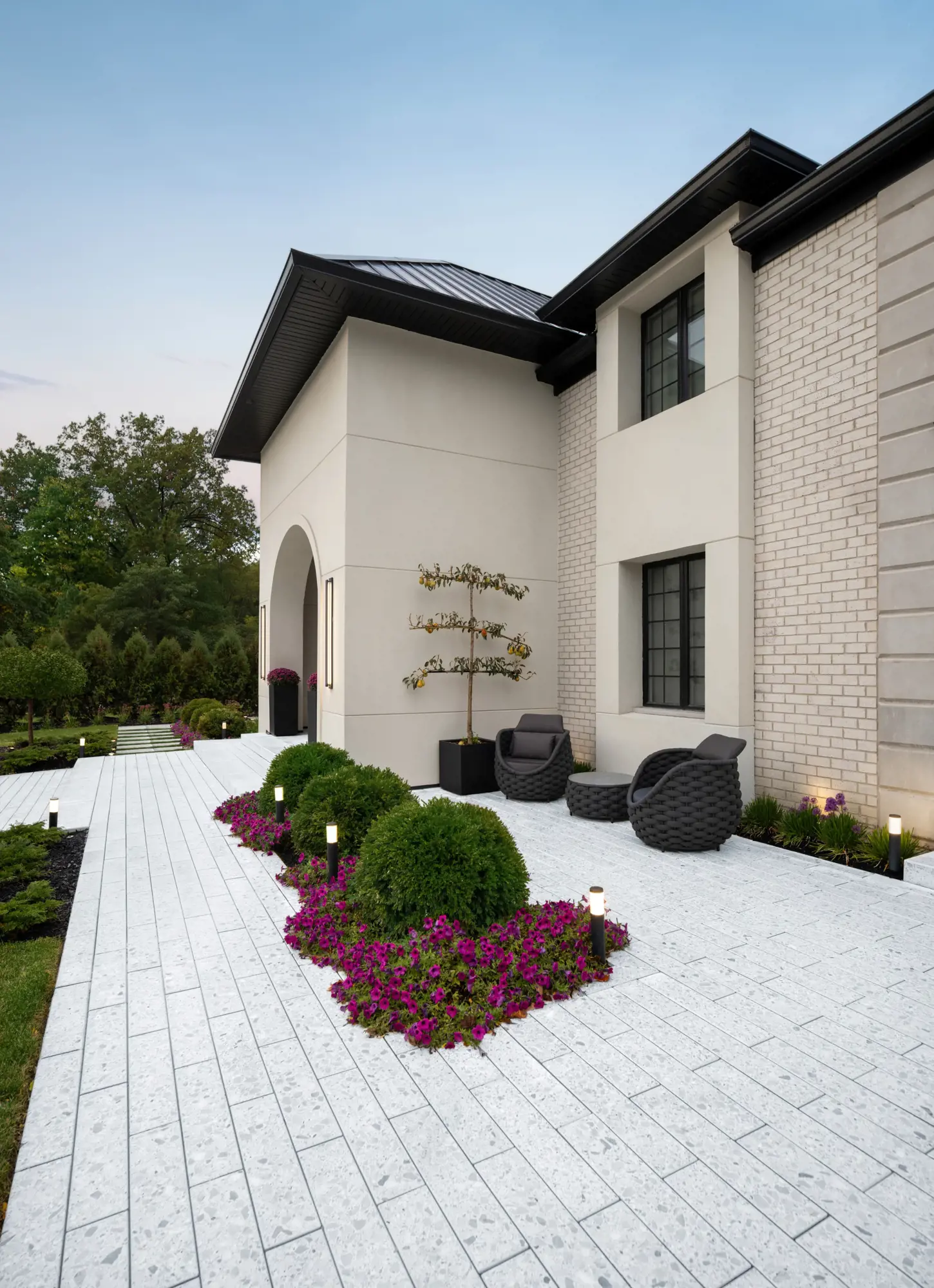 Résidence de style européen avec allée en Terrazzo Blanc Minéral, fauteuils en osier et plates-bandes fleuries